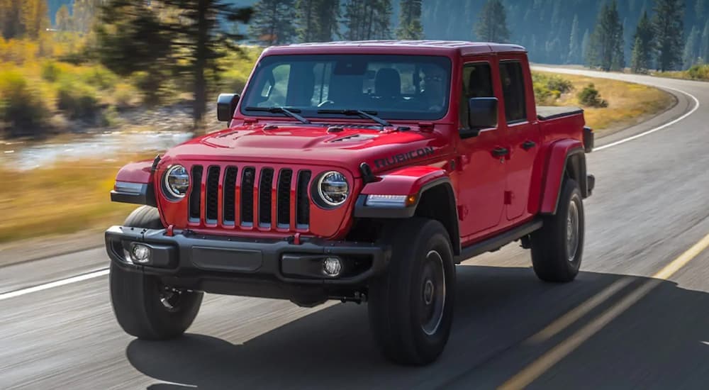 A red 2021 Jeep Gladiator is shown from the front driving on an open road.