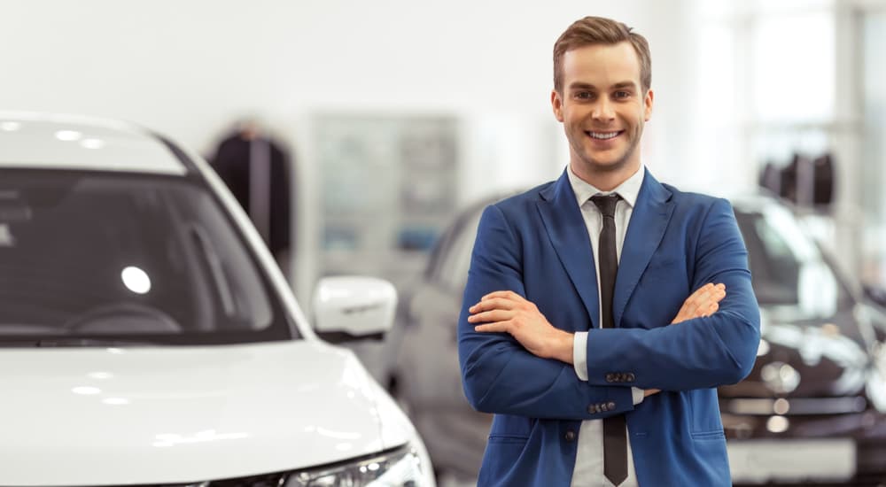 A car salesman is shown at a dealership ready to help sell your car.