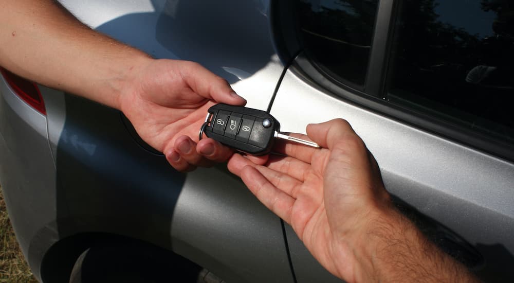 A person is shown passing a car key after learning how to sell your car.