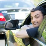 A person is shown sticking their head out the drivers side of a parked vehicle.