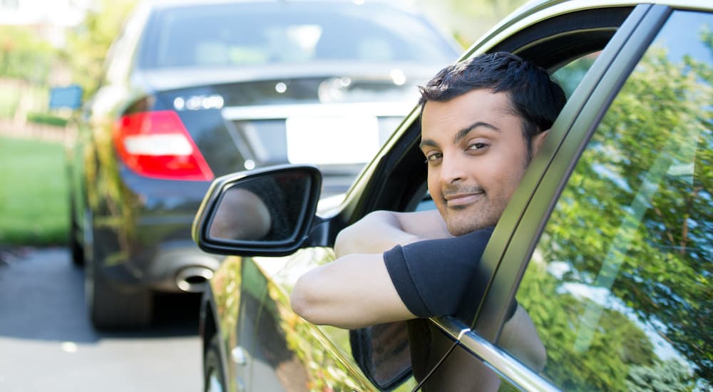 A person is shown sticking their head out the drivers side of a parked vehicle.