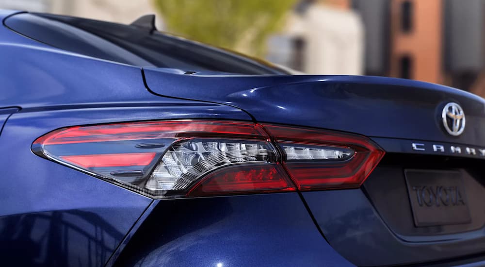 A close up shows the rear taillight of a blue 2022 Toyota Camry XLE at a Toyota Camry dealership.