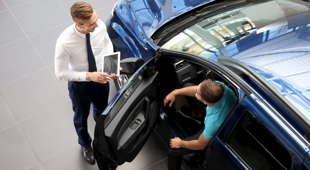 A salesman is shown speaking to a customer about a Toyota vehicle.