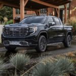 A black 2022 GMC Sierra 1500 Denali Ultimate is shown parked in front of a modern home.