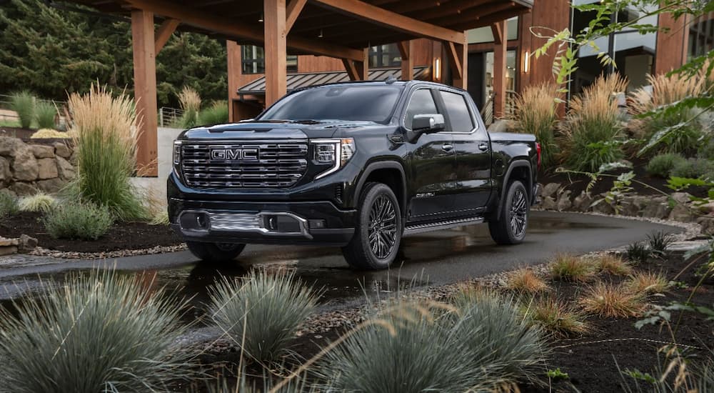 A black 2022 GMC Sierra 1500 Denali Ultimate is shown parked in front of a modern home.