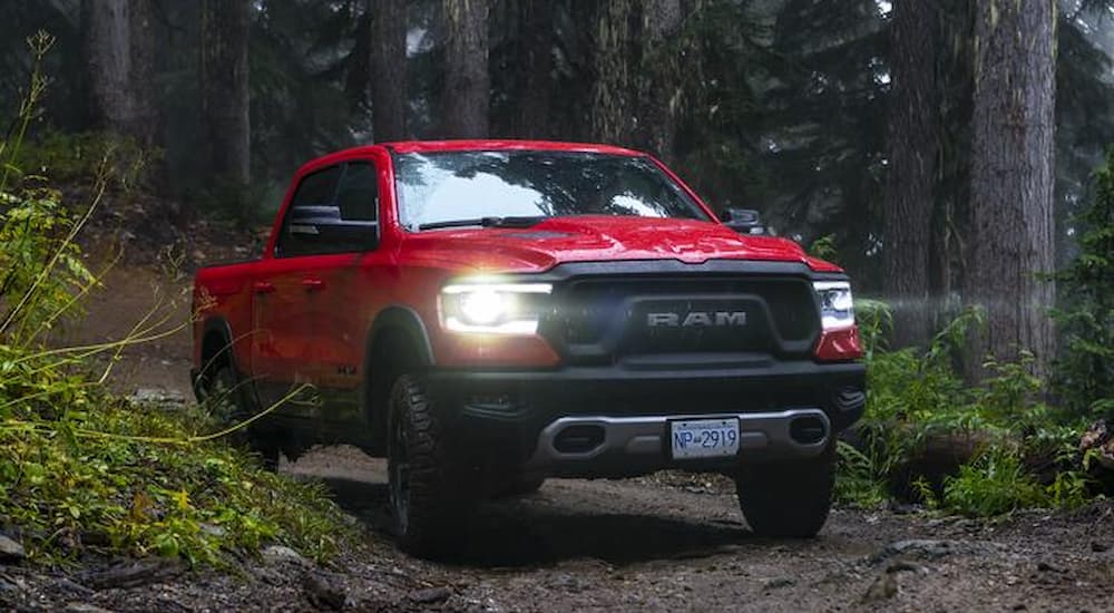 A red 2019 Ram 1500 Rebel is shown driving on a trail through the woods after leaving a used truck dealership.