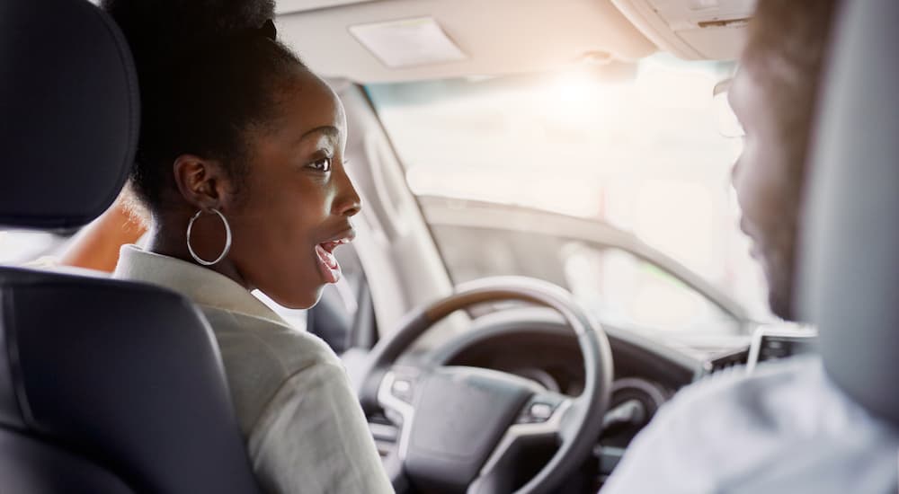 A person is shown smiling in the front seat of a vehicle.