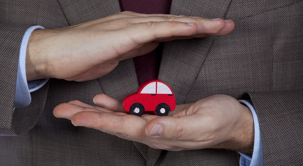 A person is shown holding a toy car as they contemplate how to sell your car.