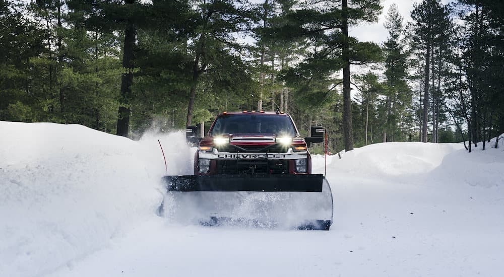 A red 2022 Chevy Silverado 3500 HD is shown from the front plowing snow.