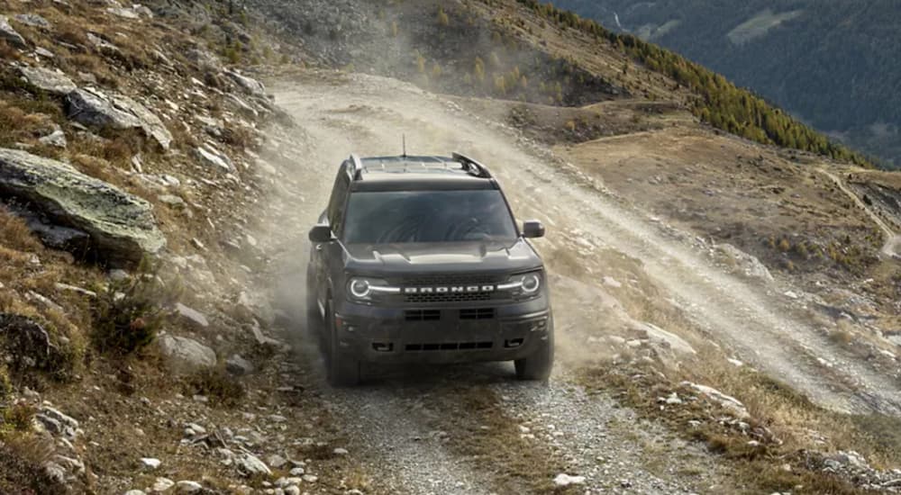 A grey 2022 Ford Bronco Sport is shown from the front driving on a dirt path. 