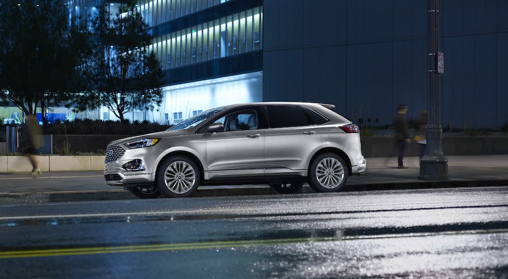 A silver 2022 Ford Edge is shown from the side parked on a city street at night.