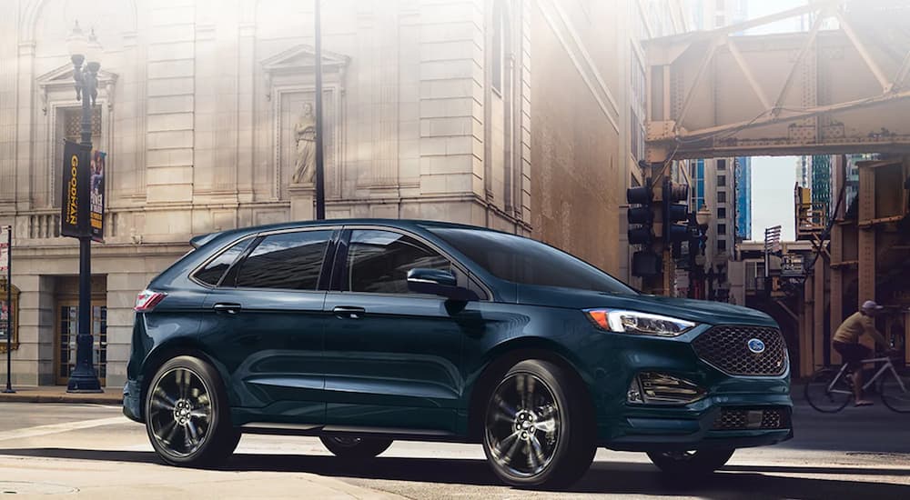 A dark blue 2022 Ford Edge ST is shown from the side driving through a city.