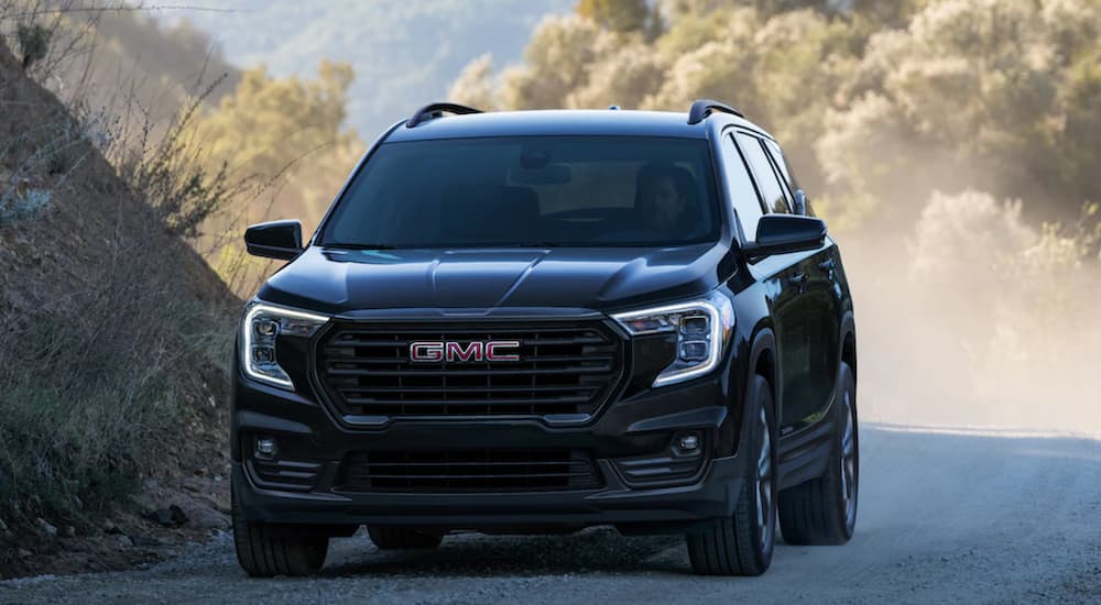 A black 2022 GMC Terrain is shown from the front driving on a dirt road.