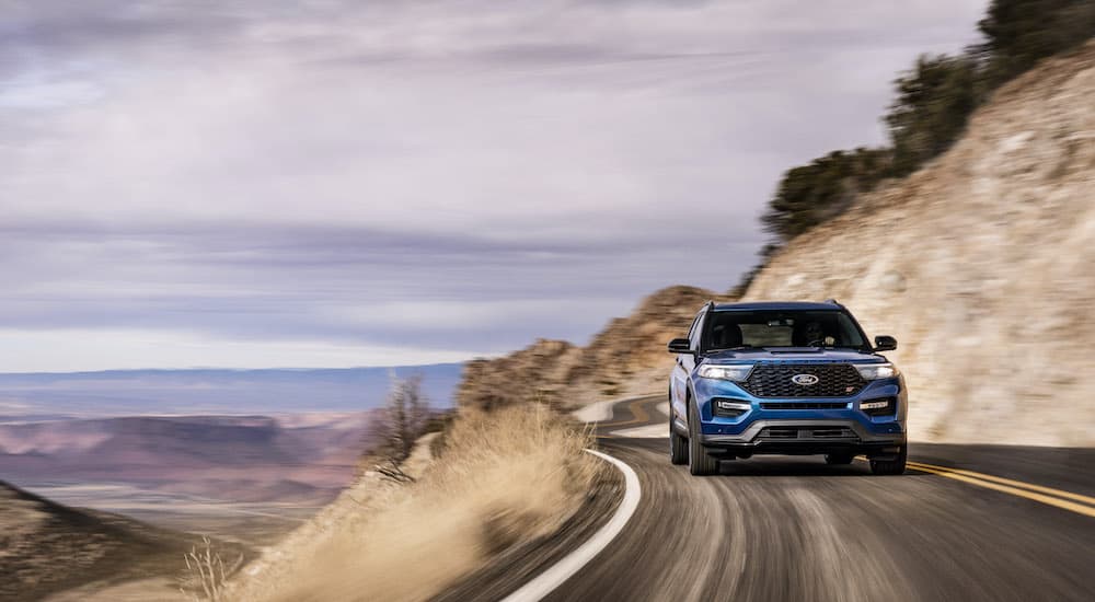 A blue 2022 Ford Explorer ST is shown driving on a winding road.