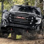 A black 2022 GMC Sierra 1500 Limited AT4 is shown from the front off-roading in the woods.