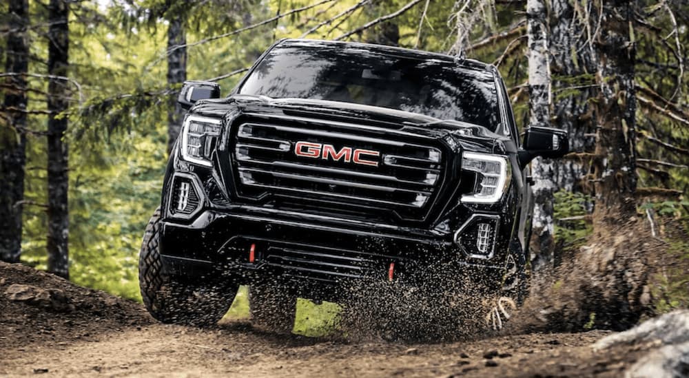 A black 2022 GMC Sierra 1500 Limited AT4 is shown from the front off-roading in the woods.