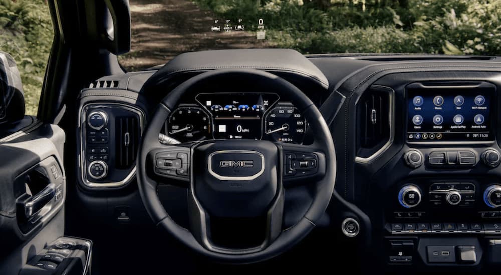 The black interior of a 2022 GMC Sierra 1500 Limited AT4 shows the steering wheel and infotainment screen.
