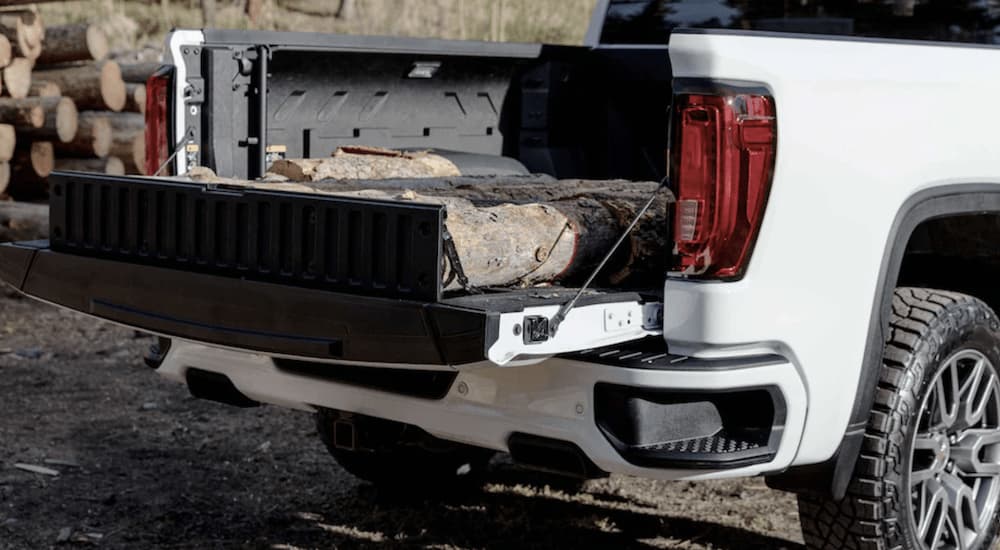 A white 2022 GMC Sierra 1500 Limited AT4 shows a row of logs in the bed of the truck.