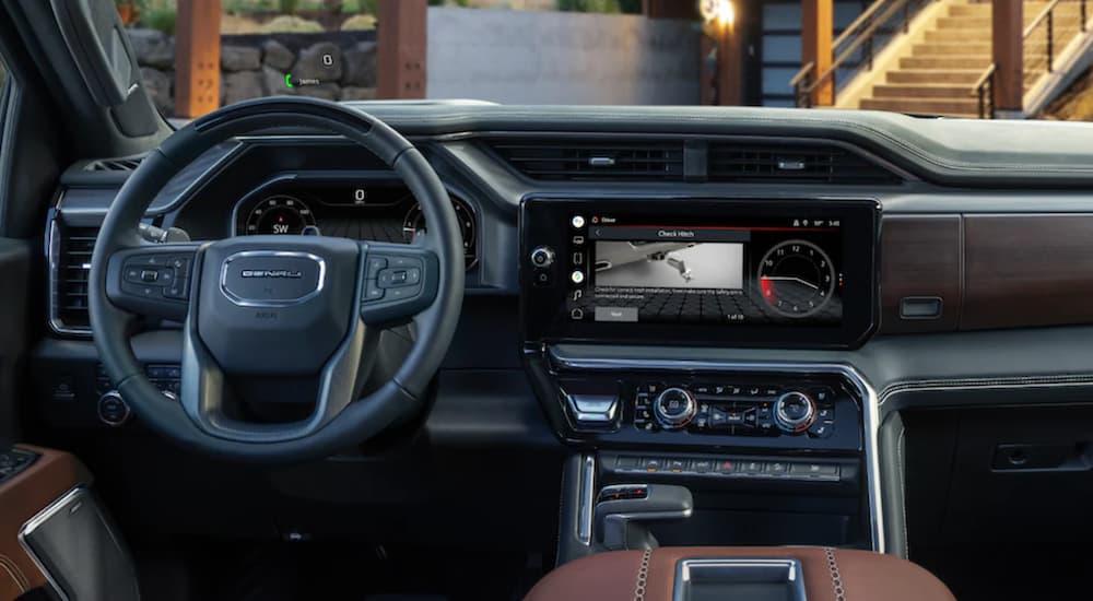 The black interior of a 2022 GMC Sierra 1500 Denali shows the steering wheel and infotainment screen.