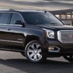 A black 2016 GMC Yukon is shown from the side parked in front of a building.