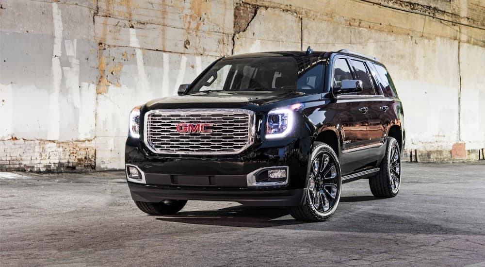 A black 2018 GMC Yukon is shown from the front parked in front of a cement wall.