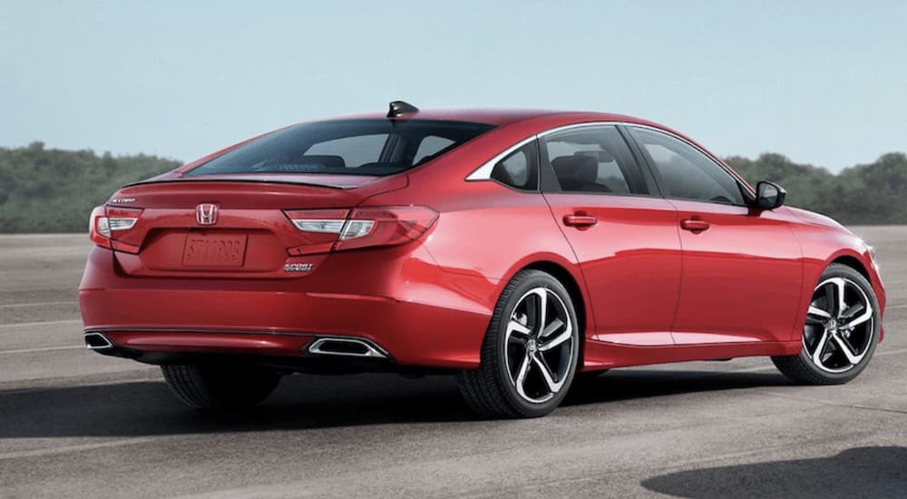 A red 2022 Honda Accord Hybrid Sport SE is shown from the side parked in an open lot.