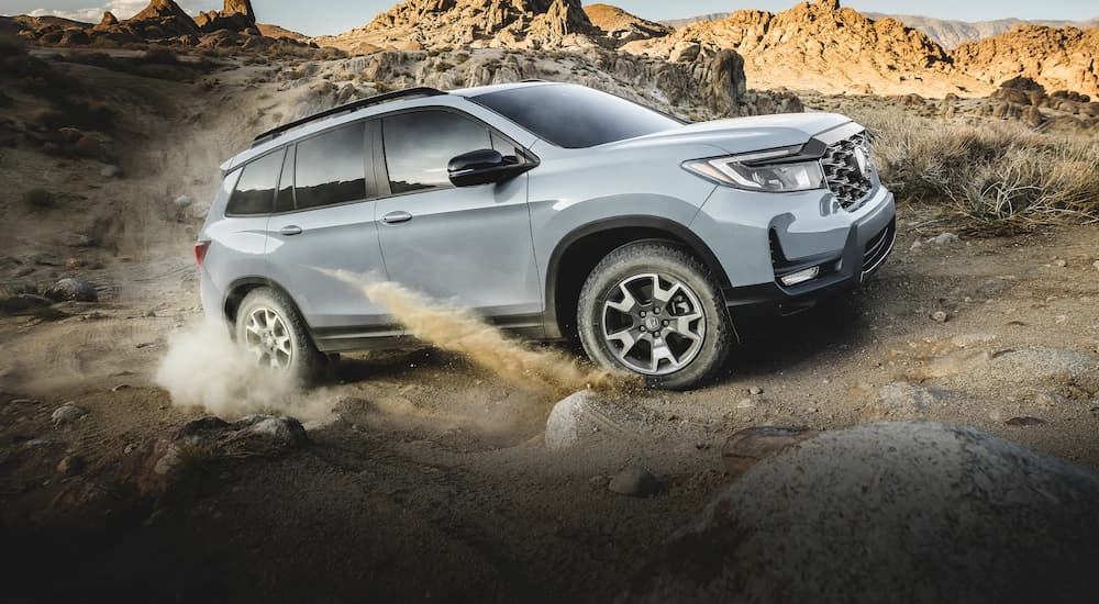 A grey 2022 Honda Passport Trailsport is shown off-roading from the side.