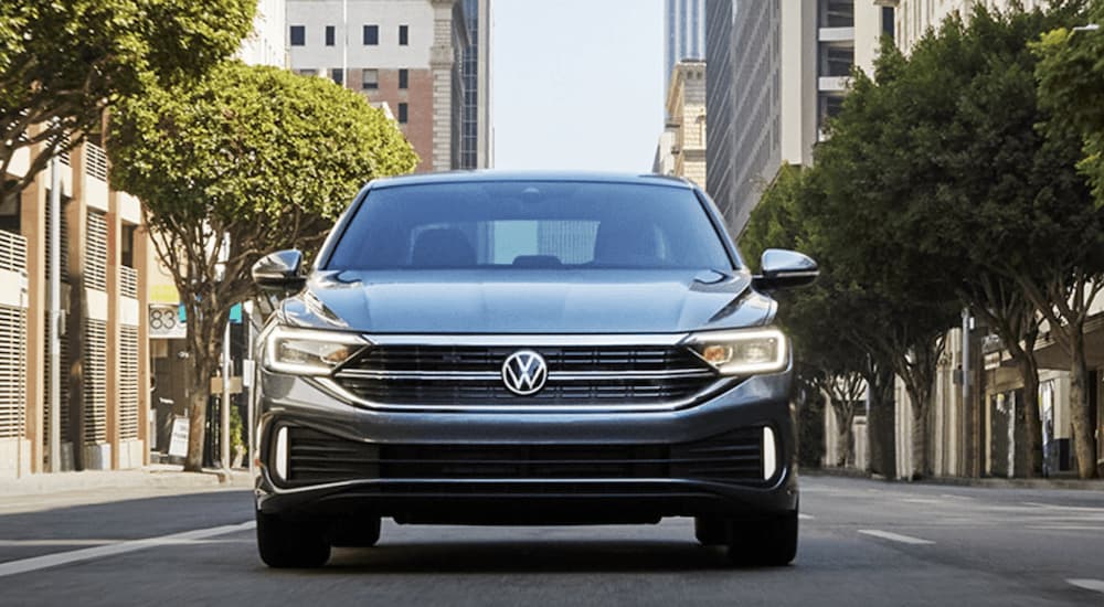 A grey 2022 Volkswagen Jetta SEL is shown from the front driving through a city.