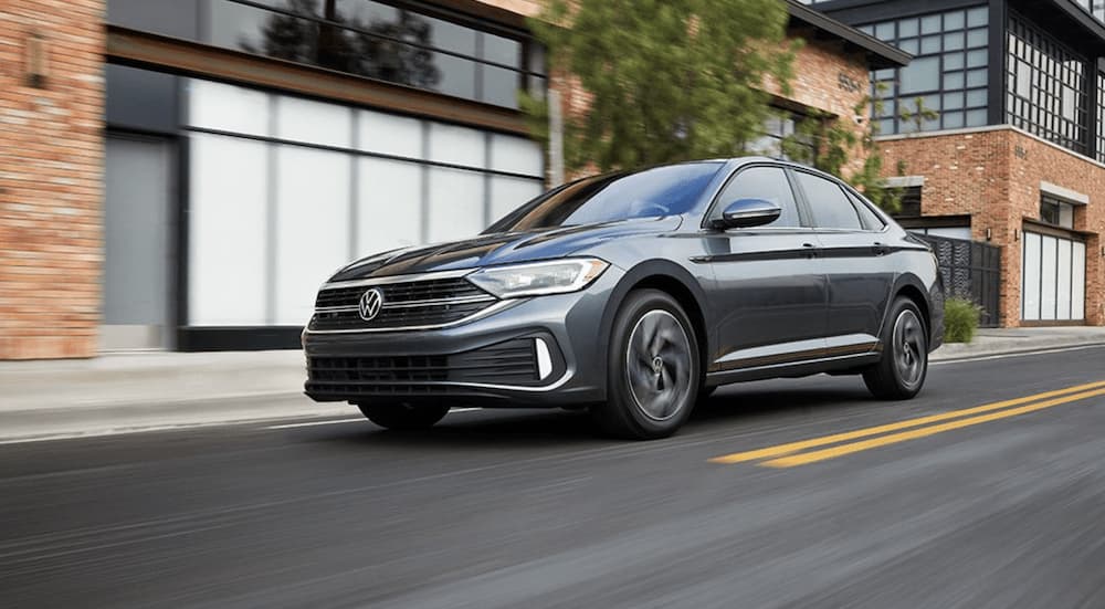 A grey 2022 Volkswagen Jetta SEL is shown from the side driving on an open road through a city.