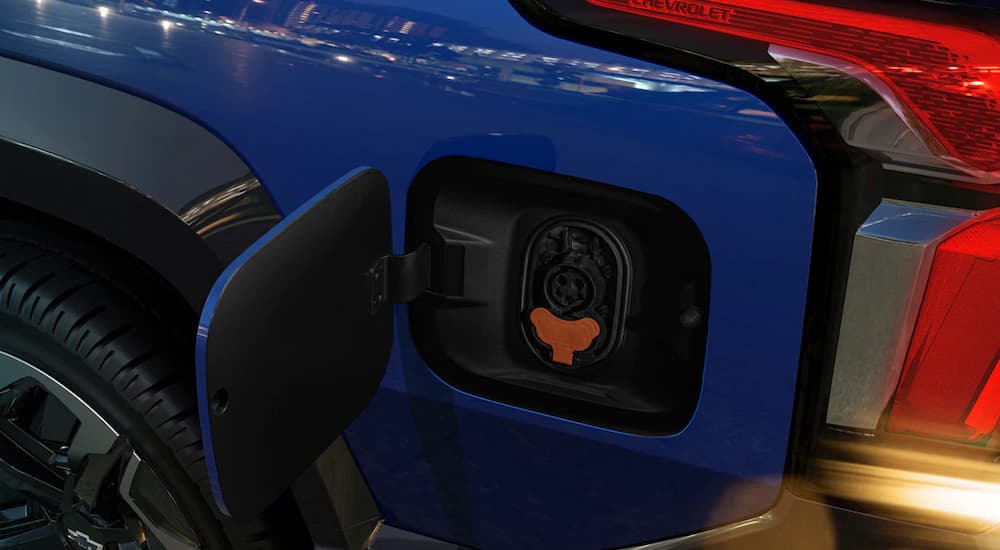 In close up a blue 2024 Chevy Silverado EV shows the charging port.