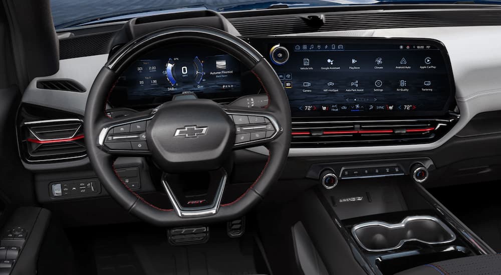 The black interior of a 2024 Chevy Silverado EV shows the steering wheel and infotainment screen.