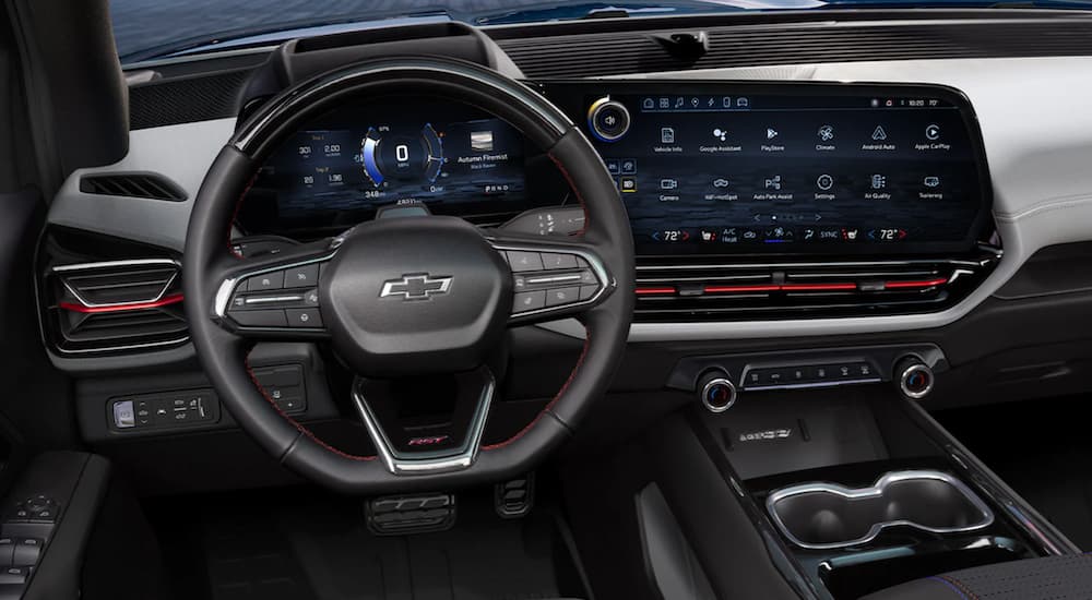 The black interior of a 2024 Chevy Silverado EV shows the steering wheel and infotainment screen.