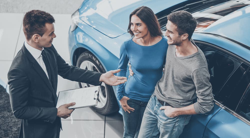 A couple is shown talking to a salesperson at a Certified Pre-Owned Ford dealer.