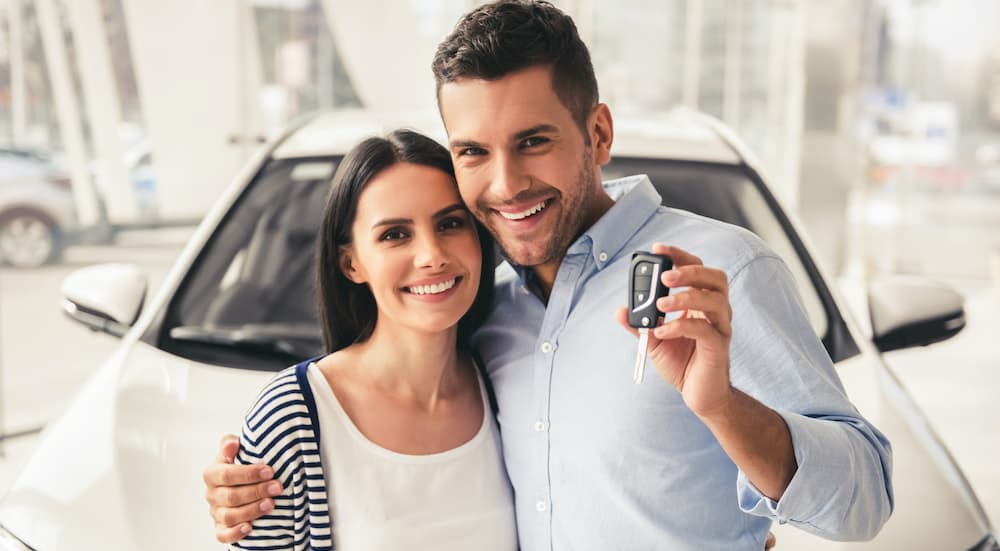 A couple is shown standing in front of a Certified Pre-Owned car.