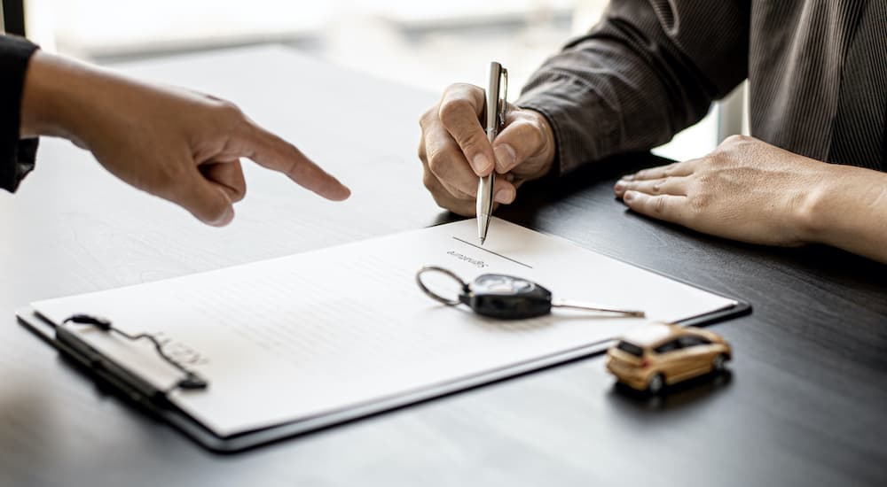 A person is shown signing paper work at a Certified Pre-Owned GMC dealer.