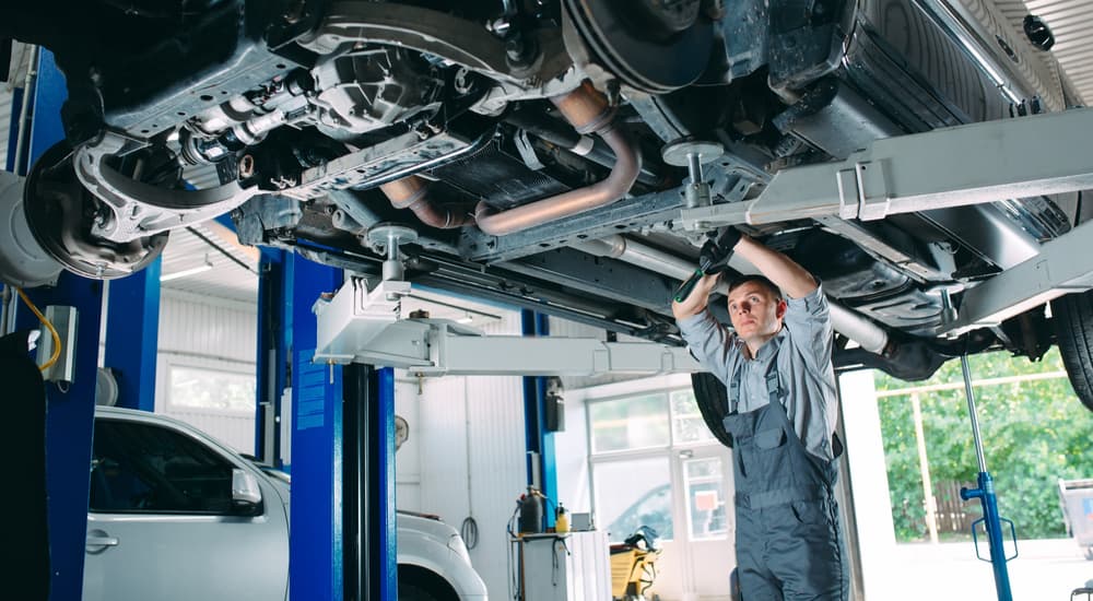 A mechanic is shown inspecting the bottom of a vehicle up on a lift.