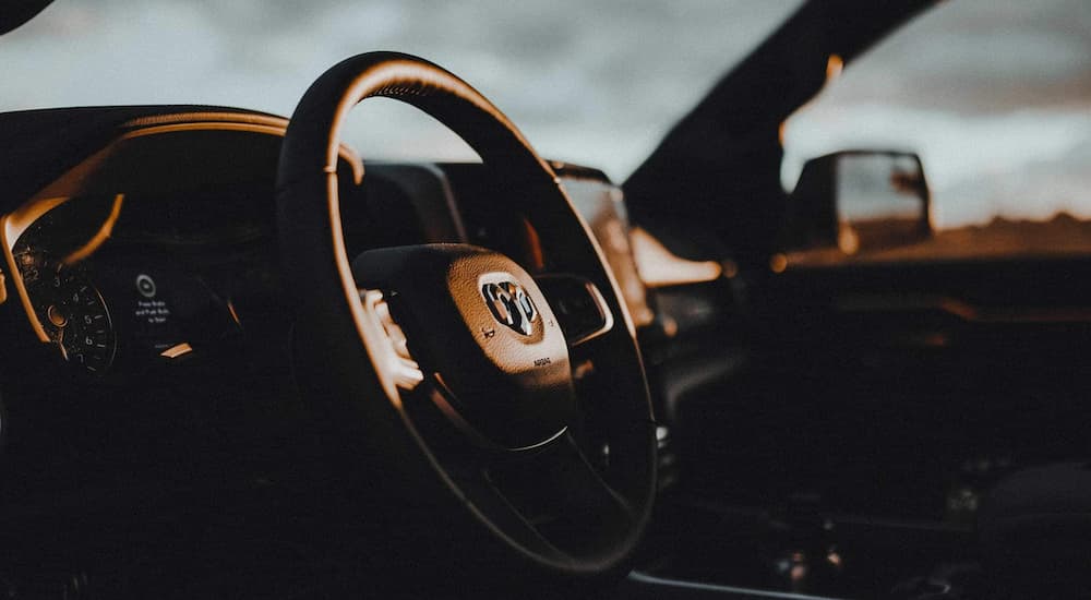 The black interior of a 2022 Ram 1500 shows the steering wheel.