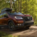 A brown 2022 Honda Passport is shown from the front at an angle while driving through the woods.