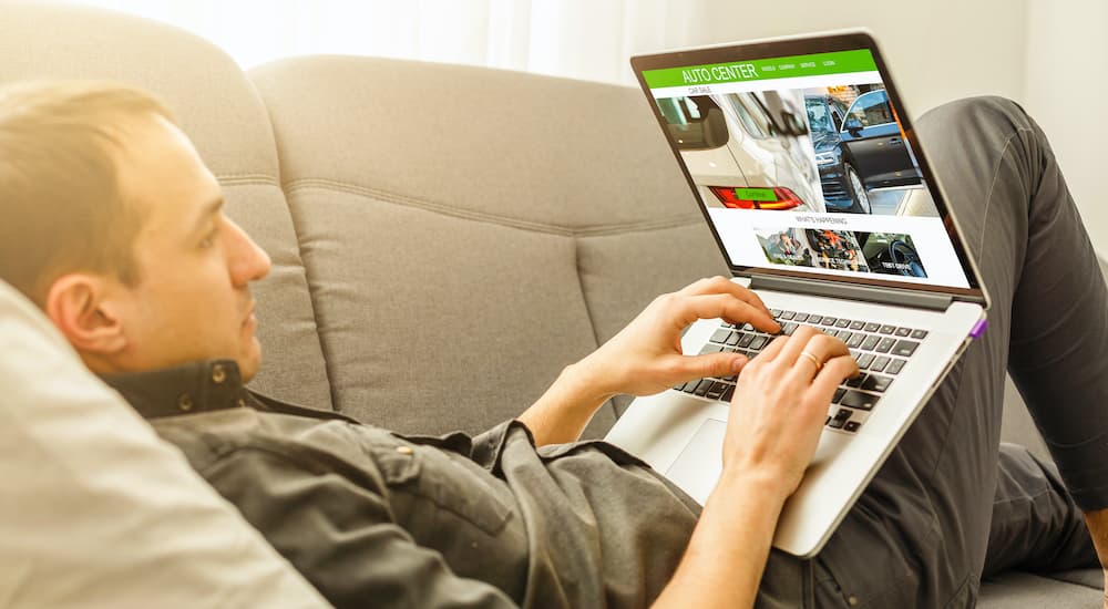 A person is shown searching fro a car on a laptop.