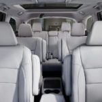 The white interior of a 2020 Honda Pilot Touring shows three rows of seating.