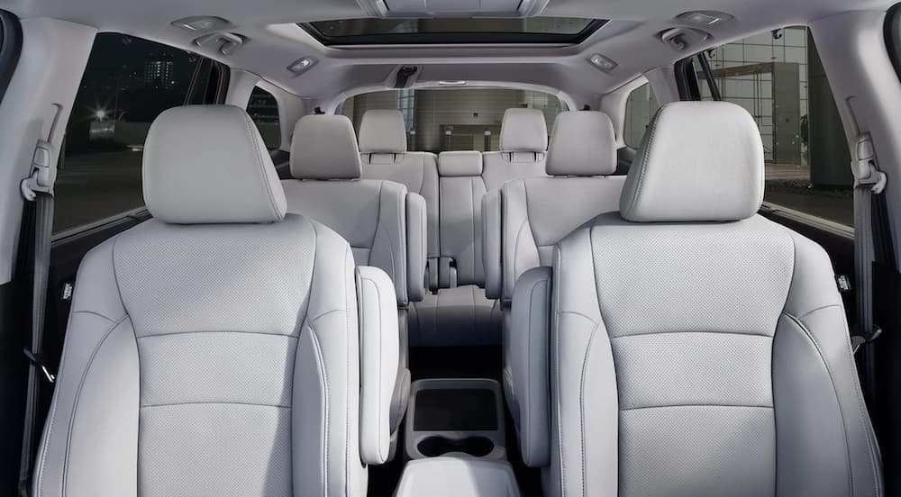 The white interior of a 2020 Honda Pilot Touring shows three rows of seating.