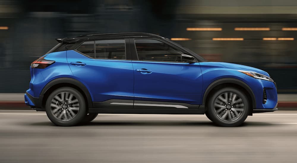 A blue 2021 Nissan Kicks is shown from the side driving on an open road.