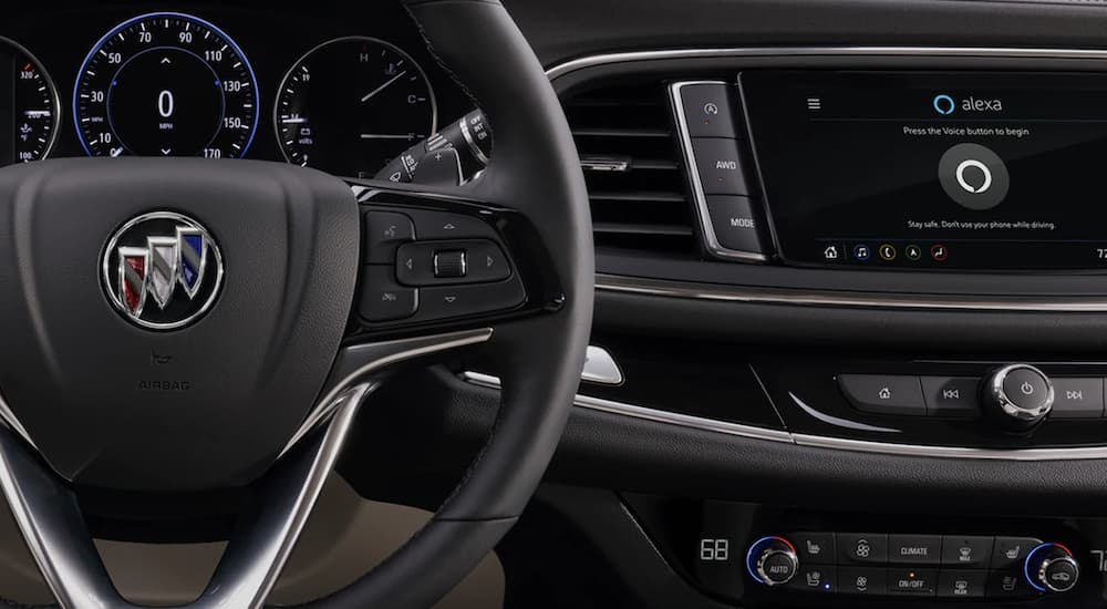 The black interior of a 2022 Buick Enclave shows the steering wheel and infotainment screen.