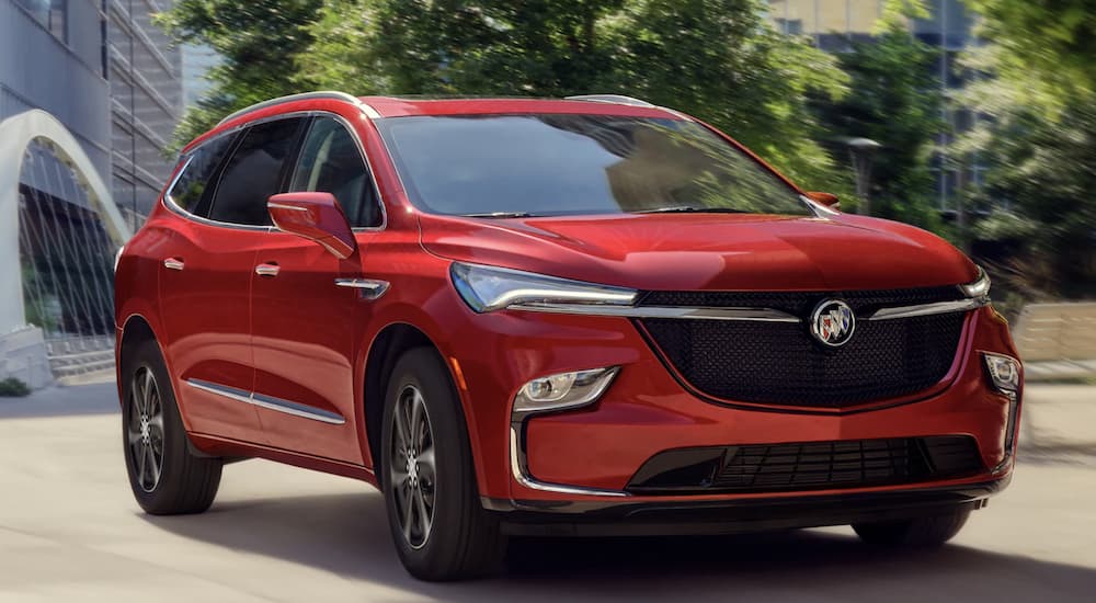 A red 2022 Buick Enclave is shown from the front driving through a city.