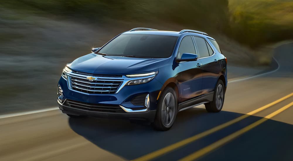 A blue 2022 Chevy Equinox is shown from the front driving on an open road.
