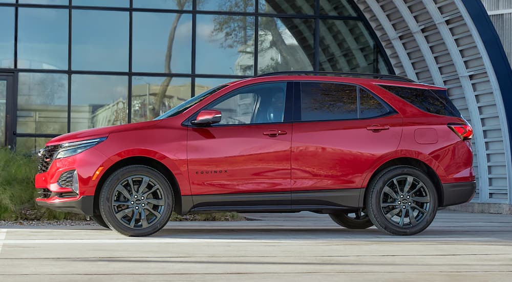 A red 2022 Chevy Equinox is shown from the side parked in front of a glass building.