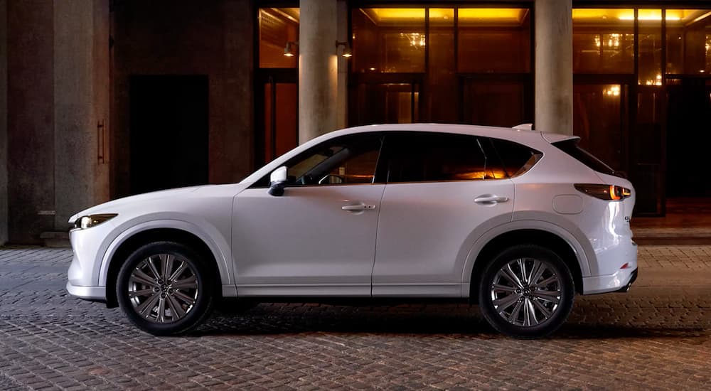 A white 2022 Mazda CX-5 is shown from the side parked in front of a building at night.