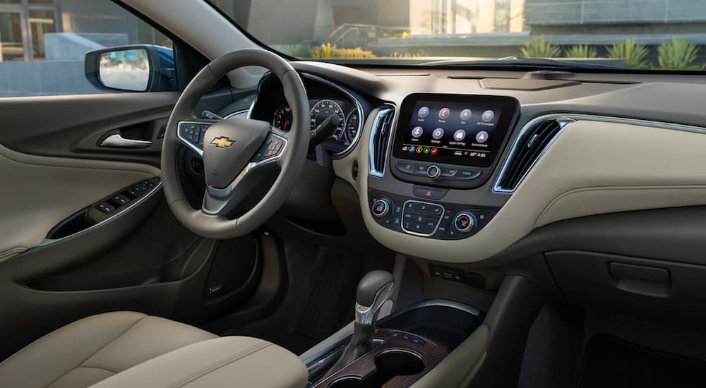The tan interior of a 2022 Chevy Malibu shows the steering wheel and infotainment screen.