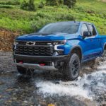 A blue 2022 Chevy Silverado 1500 ZR2 is shown off-roading through a river.