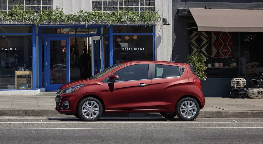 A red 2022 Chevy Spark  is shown from the side parked in front of a building.